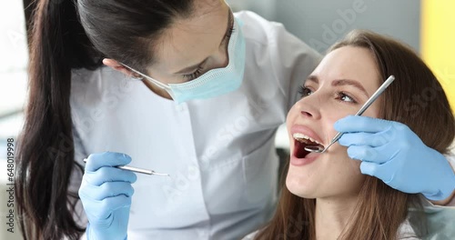 Dentist with protective mask examining teeth of female patient 4k movie. Dental care concept photo
