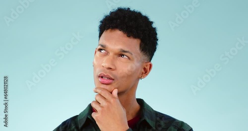 Thinking, idea and young man in a studio with dreaming, guess or question facial expression. Remember, reflection and model from Mexico with curious, solution or brainstorming face by blue background