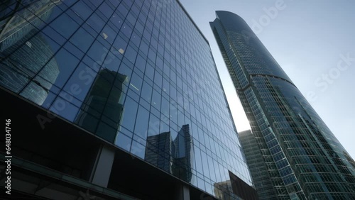 The mirrored facade of the Moscow City business center in the reflection of other skyscrapers. The glare of the sun in the reflection of mirrored modern buildings. Dolly camera