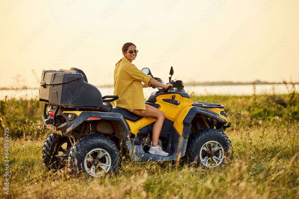 Portrait of a smiling woman driving a rented quad bike, with sunglasses on. Portrait of a smiling woman driving a rented quad bike, with sunglasses on.