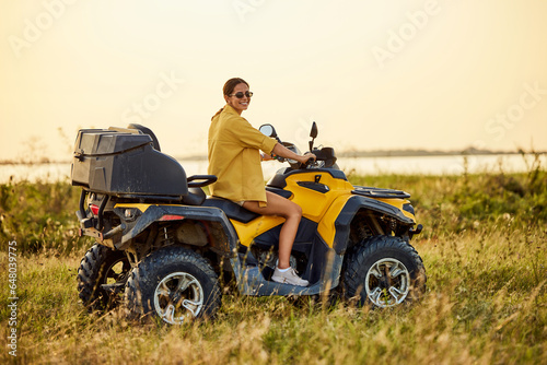Portrait of a smiling woman driving a rented quad bike, with sunglasses on.