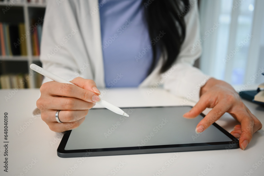 Young woman using stylus pen writing notes on digital tablet, freelancer working at home Young woman using stylus pen writing notes on digital tablet, freelancer working at home