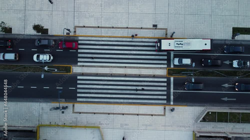 People cross a zebra crossing, a bus enters a pedestrian crossing