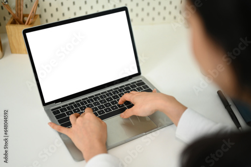 View over shoulder view of young woman hands typing on laptop keyboard. Blank screen for your advertising text message