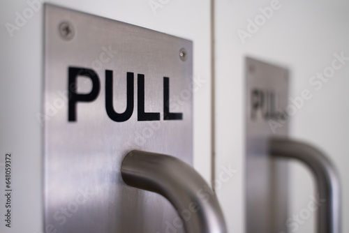 Door pull sign, door handle affixed to the glass background of an office door