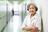 Portrait of smiling old asian female doctor standing with arms crossed in hospital corridor