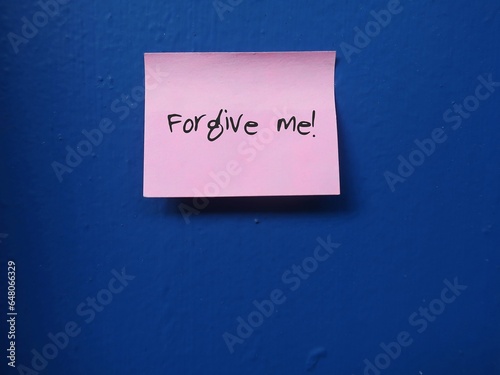 Pink note stick on blue wall with handwritten text FORGIVE ME !, to ask someone to forgive, toapologize, to say sorry for making mistake