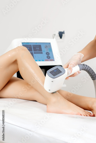 Cuadro en lienzo A female cosmetologist does laser hair removal on the slender legs of a beautiful young woman lying on a medical couch in a beauty salon