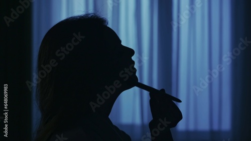 Woman in bathrobe sitting on a chair in the room, applying powder with brush. Closeup shot of the face.