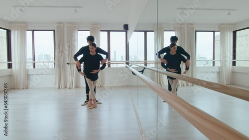Young ballet duet practicing synchronic moves in modern spacious dance studio with mirror wall. Full shot, copy space photo