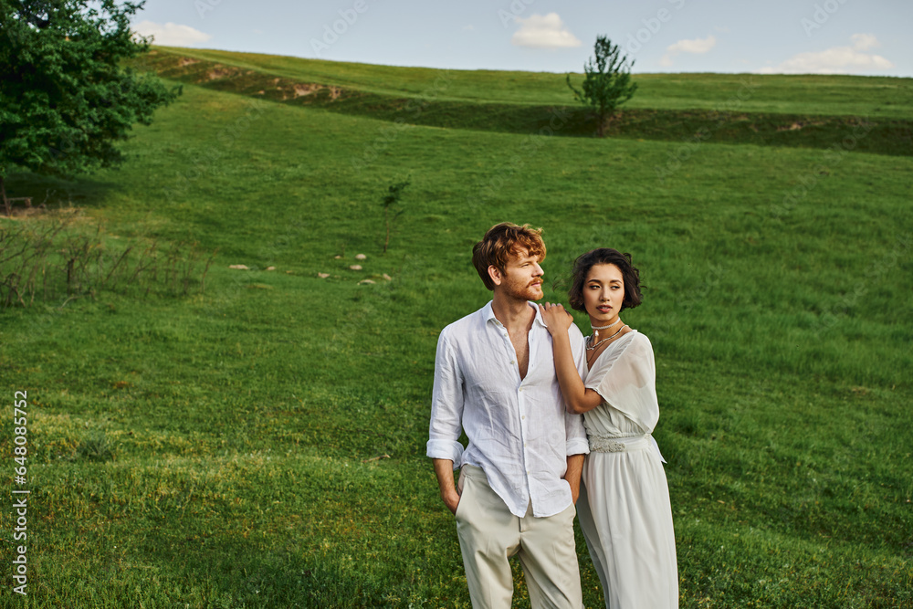 just married interracial couple standing together in green field, scenic and tranquil landscape just married interracial couple standing together in green field, scenic and tranquil landscape