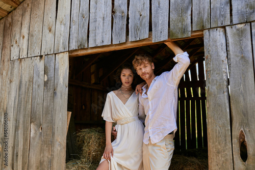 newlyweds in countryside, pretty asian bride in white dress standing with groom in wooden barn © LIGHTFIELD STUDIOS