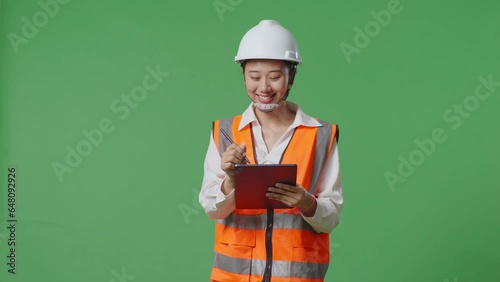 Asian Female Engineer With Safety Helmet Using Tablet While Walking In The Green Screen Background Studio
 photo