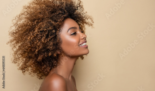 Beautiful black woman . Beauty portrait of african american woman with clean healthy skin on beige background. Smiling beautiful afro girl.Curly black hair . Afro Hairstyle