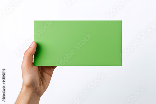 A human hand holding a blank sheet of green paper or card isolated on a white background