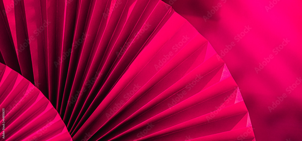 Background with vibrant large pink purple paper oriental craft fans. Dark texture banner with deep shadows. Chinese New Year celebration. Traditional decor for lunar calendar party.Festive decoration