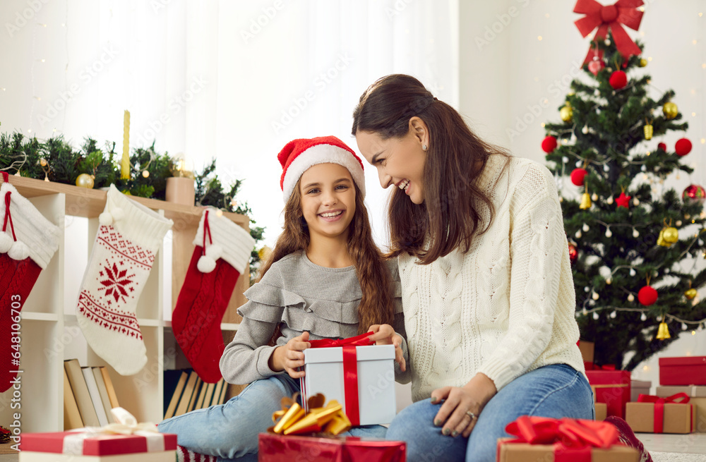 New Year and Christmas is coming. Portrait of young mother and her teenage daughter sitting among Christmas presents. Family sitting on floor in room with Christmas decorations and Christmas tree. New Year and Christmas is coming. Portrait of young mother and her teenage daughter sitting among Christmas presents. Family sitting on floor in room with Christmas decorations and Christmas tree.