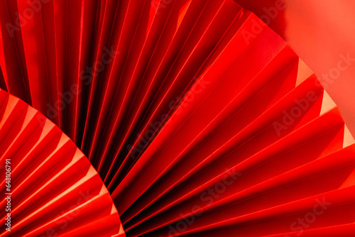 Background with vibrant bright red paper oriental craft fans. Dark texture banner with deep shadows. Chinese New Year celebration. Traditional decor for lunar calendar party.Festive decoration
