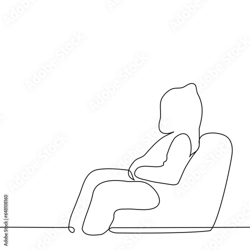 person in a hoodie with a hood on and hands in his pockets sits in profile in an easy chair - one line art vector. concept unknown, anonymous, noname, hacker
