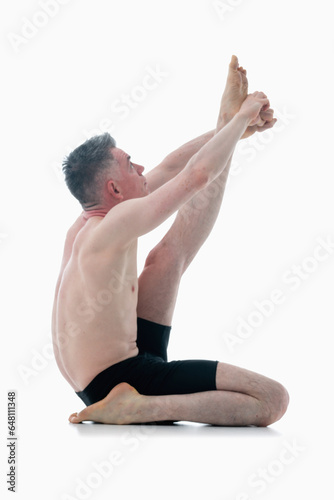 Krounchasana (Heron Pose), Ashtanga yoga  Side view of man wearing sportswear doing Yoga exercise against white background. Vertical image. photo