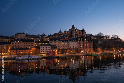Old buildings with their lights in central Stockholm at dusk, overlooking the lake, on a calm winter day.