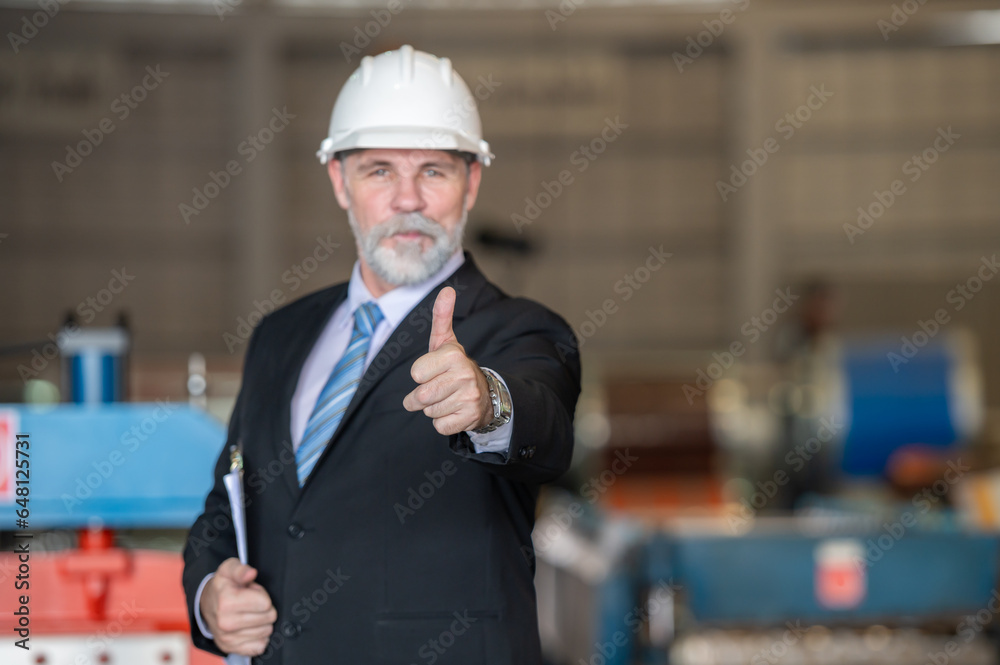 older owner engineer with beard mustache on face standing smile with his arms crossed at construction factory site. Boss manager in suit show good thumb at factory industry site. older owner engineer with beard mustache on face standing smile with his arms crossed at construction factory site. Boss manager in suit show good thumb at factory industry site.