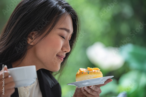 Asian girl holding look surprise dessert cake in hand and smell taste sweet cream. Smiling woman eating fancy piece of chocolate fruit cake in birthday celebration party.