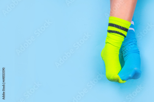 Odd Socks Day, Lonely Sock Day. Anti-Bullying Week, Down syndrome awareness. Child legs wearing different pair of mismatched socks on high-colored background copy space