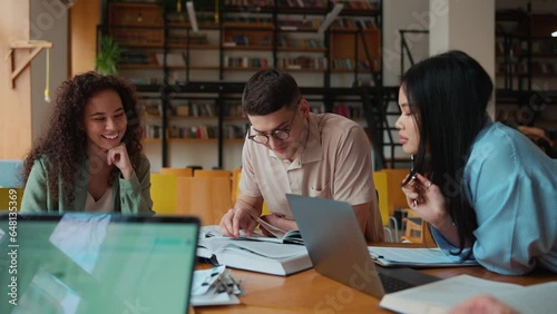 Group of positive multicultural students studying and talking in the library