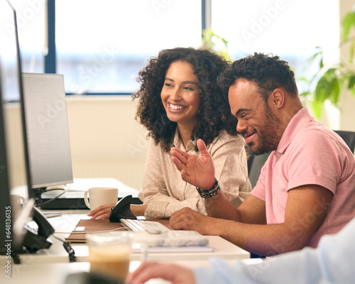 Obraz na płótnie Woman Working In Office Based Business Training Man With Down Syndrome Using Com