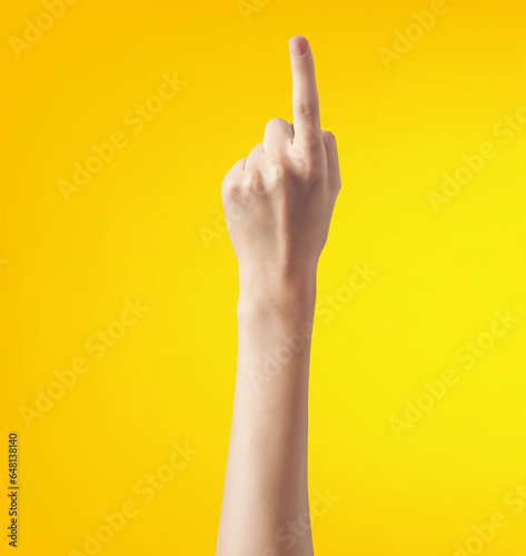 Female hand showing the middle finger on a yellow background with copy space