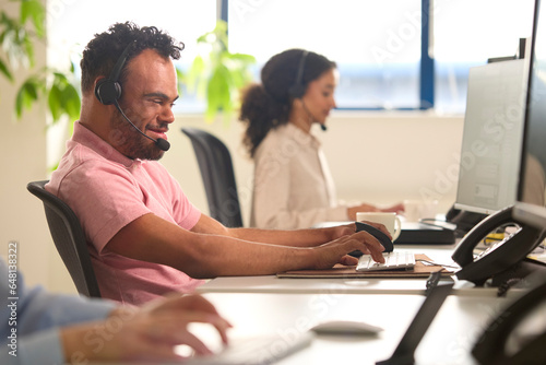 Man With Down Syndrome Wearing Headset Working In Office Call Centre Team