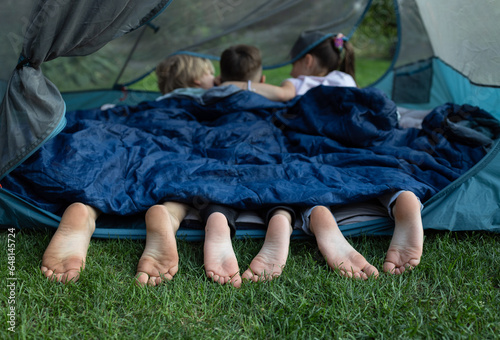 Konstfotografi cute bare feet of three children peeking out of sleeping bag
