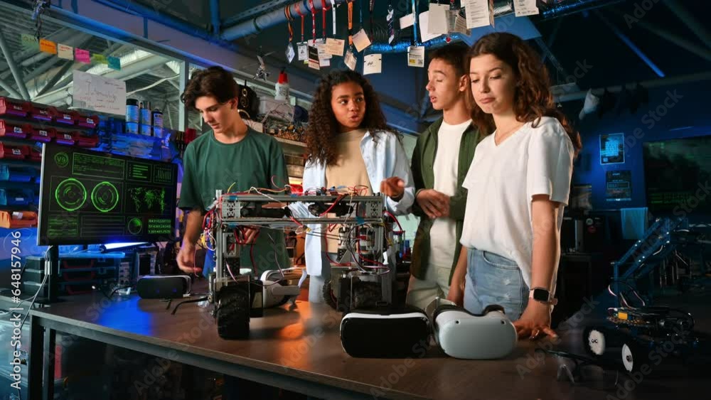 Group of young people discussing and putting on VR glasses while doing experiments in robotics in a laboratory. Robot on the table Group of young people discussing and putting on VR glasses while doing experiments in robotics in a laboratory. Robot on the table