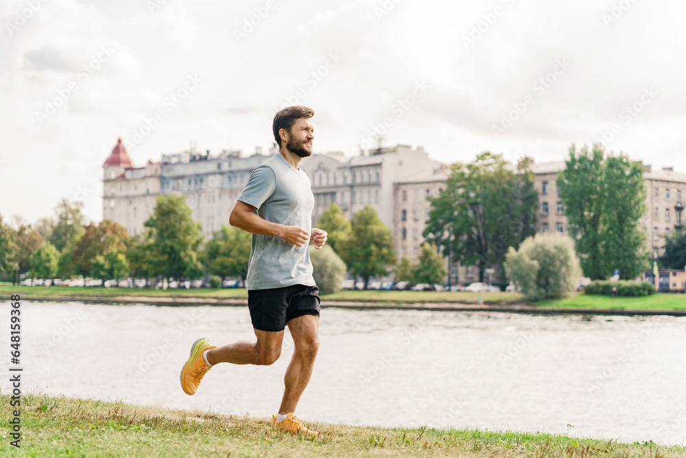 Running athlete trainer fitness exercises for cardio and health. A man in sportswear doing a workout.  A sporty confident person running in the city.    Uses a fitness watch and an app.