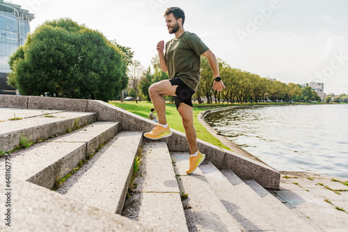 A sporty confident person running in the park. A man in sportswear doing a workout. Running trainer fitness exercises for cardio and health. Uses a fitness watch and an app.