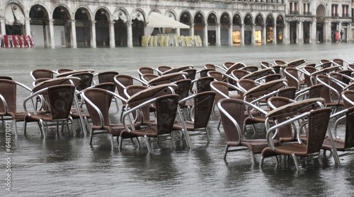 Fotografia High tide in Venice Island in Italy chairs of the outdoor cafe in Saint Mark squ