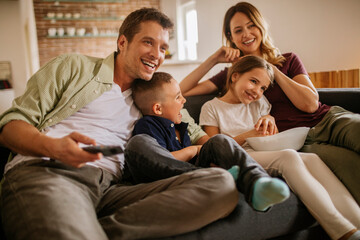 Happy young Caucasian family watching a movie together in the living room