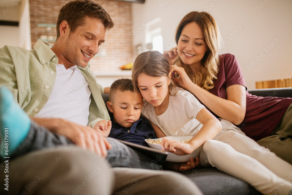 Young caucasian family using a tablet on the couch in the living room