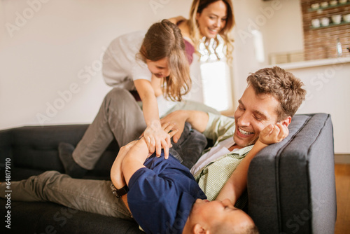 Young caucasian family having fun and being playful on a couch in a living room
