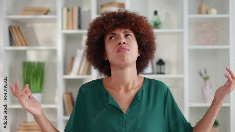 Confused african american woman in collarless blouse getting disappointed while standing in living room. Young attractive housewife feeling upset because of family issues in modern apartment. Confused african american woman in collarless blouse getting disappointed while standing in living room. Young attractive housewife feeling upset because of family issues in modern apartment.