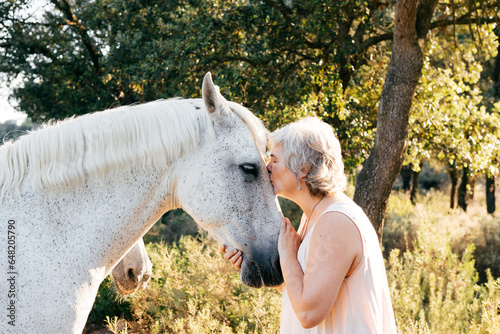 Photography Senior woman kissing gray horse on sunny summer day