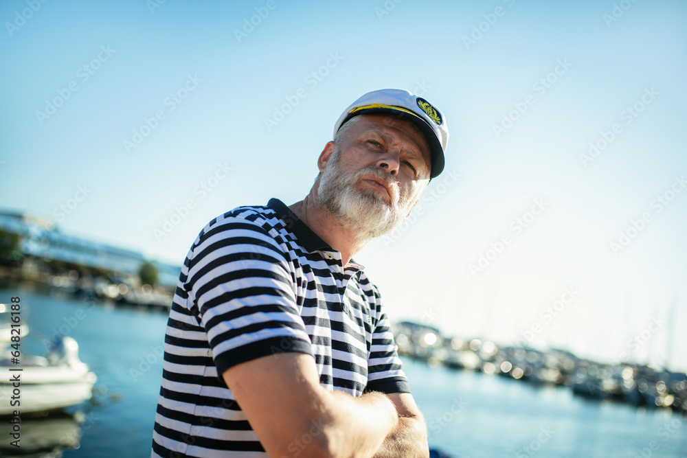 Mature man standing near the sea dressed in a sailor's shirt and hat.