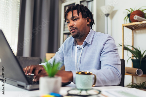 Handsome African American smiling freelancer working remotely from home