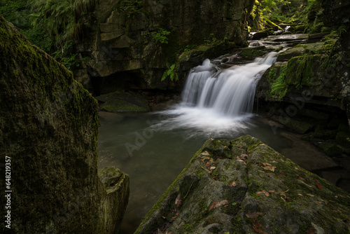 A small waterfall between stones in the forest.