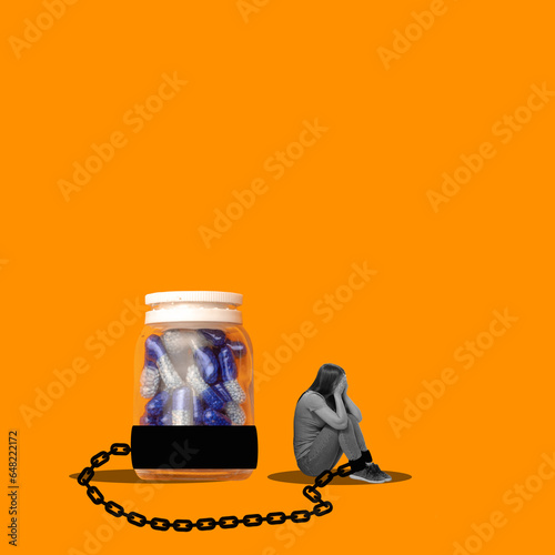 Young girl sitting in depression on floor with chain to giant bottle with pills. Conceptual design. Concept of addiction, psychology, medical treatment, healthcare, surrealism. Contemporary artwork