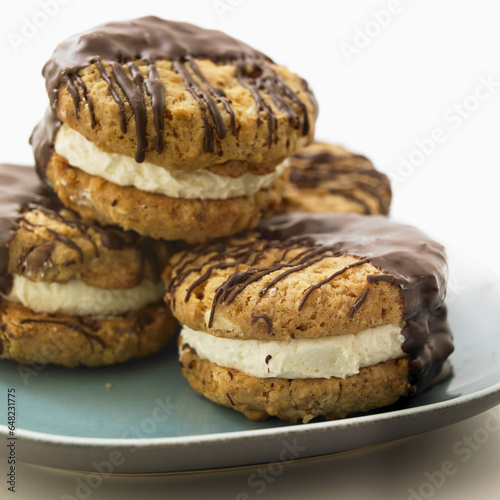Four Chocolate Dipped Sandwich Cookies Stacked On A Teal Plate; Victoria, British Columbia, Canada photo