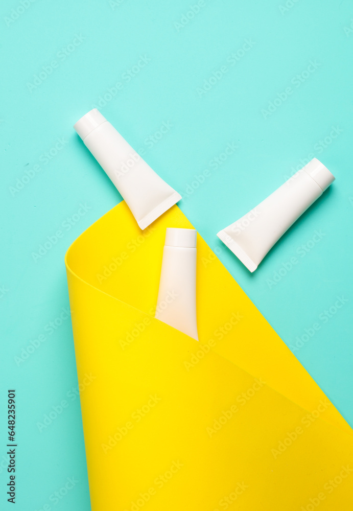White cream tubes on a blue yellow background. Creative layout. Top view White cream tubes on a blue yellow background. Creative layout. Top view