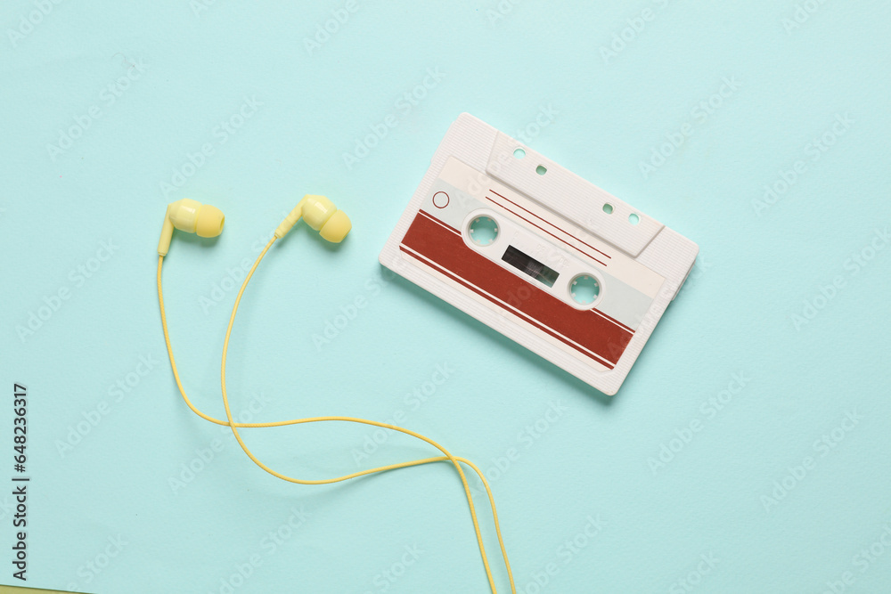 Retro 80s audio cassette with earphones on a blue background Retro 80s audio cassette with earphones on a blue background