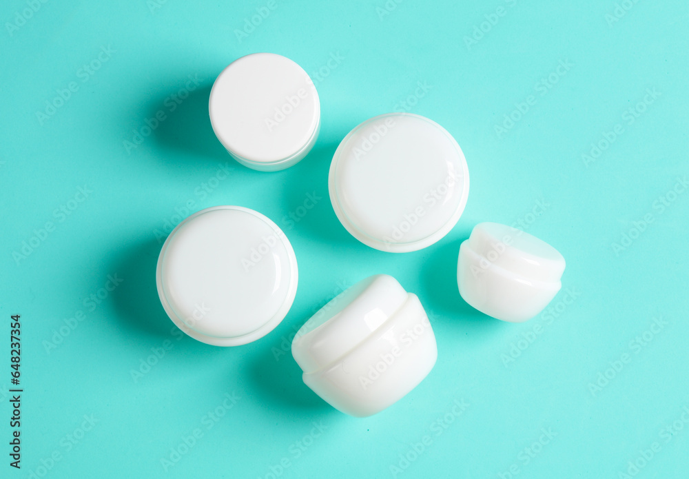 White cream jars on a blue background. Mockup, template for design. Top view White cream jars on a blue background. Mockup, template for design. Top view